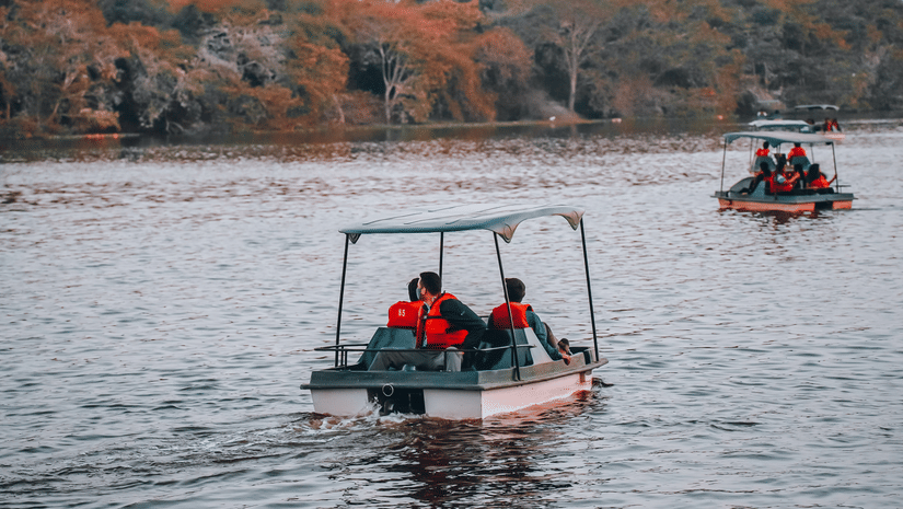 A group of people wearing life jackets on a boat ride on a lake during daytime.