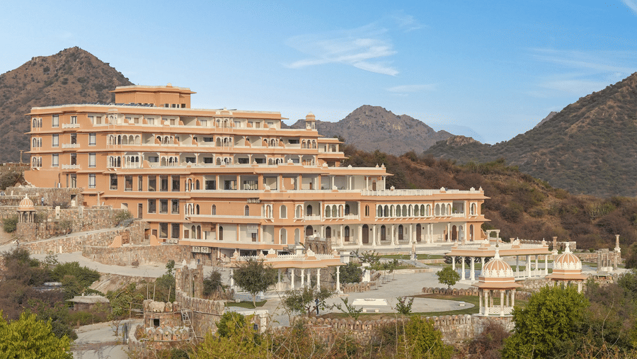 Location of Fateh Vilas by Fateh Collection with many trees in the foreground and mountains in the background