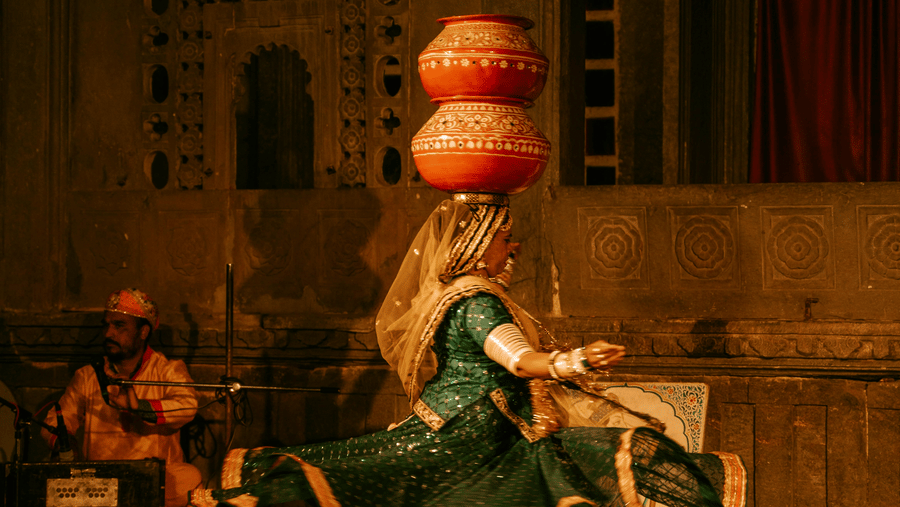 A female Rajasthani folk dancer with a couple of earthen pots on her head on the stage