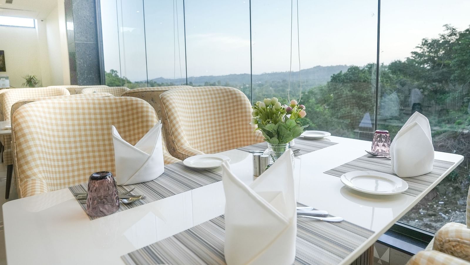 A close-up shot of a dining table situated near a large window, providing views of the mountains at our restaurant in Kangra - NAMAMI BY ZENQ BANKHANDI