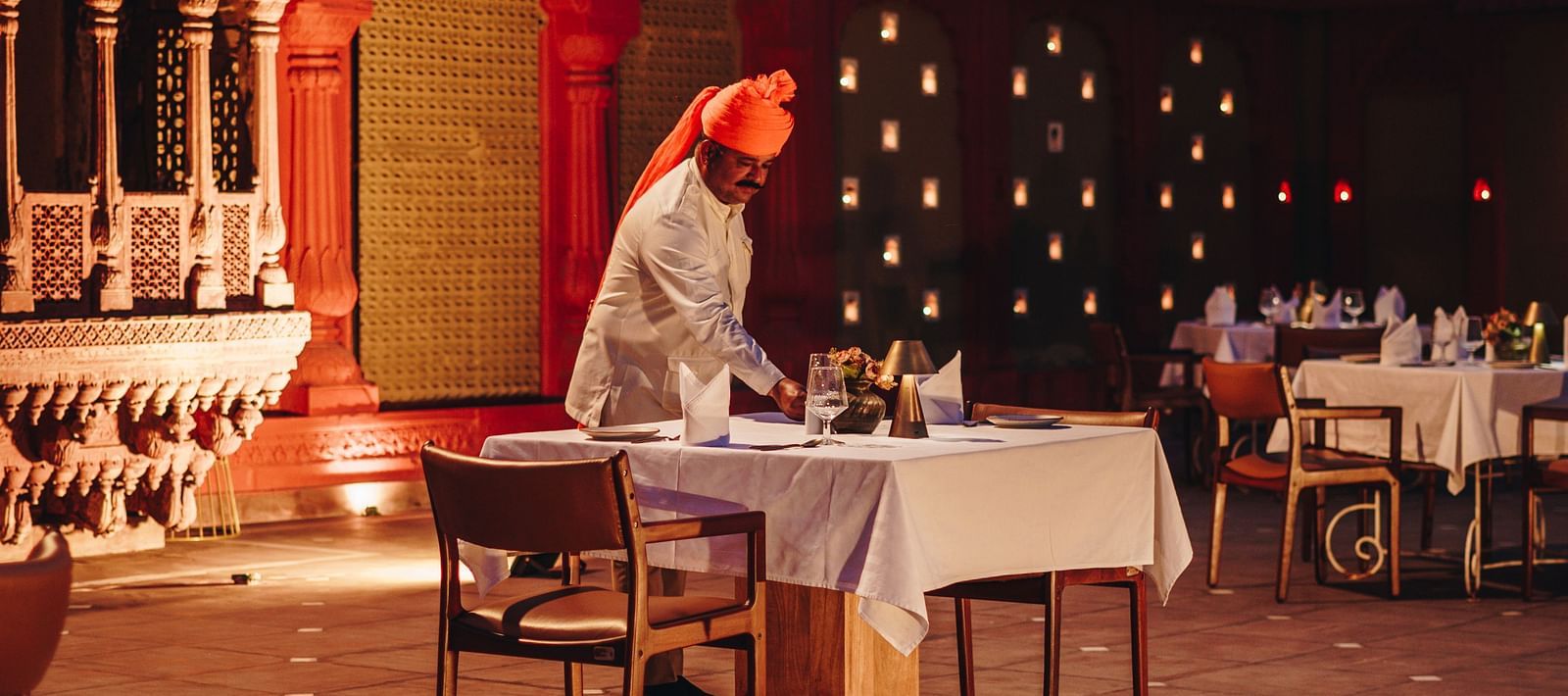 An outdoor dining setup with a traditionally dressed server at Surpura Bagh.