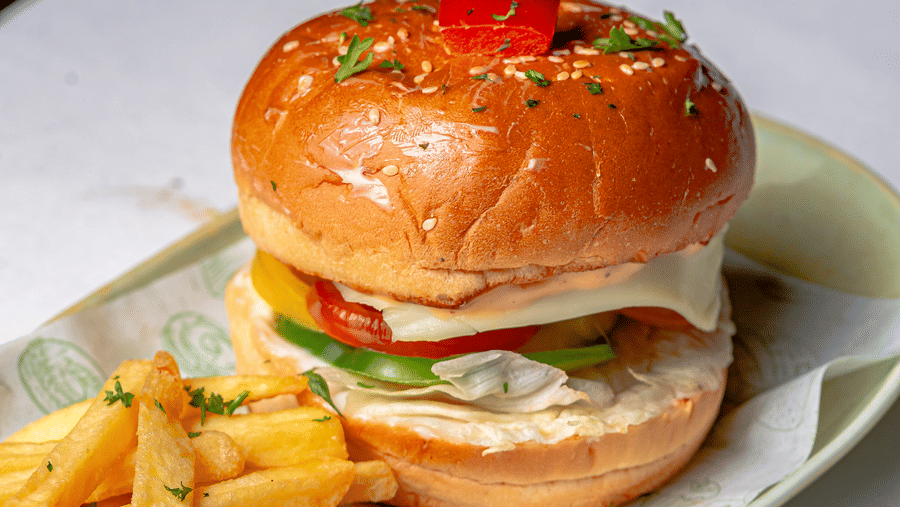 Close-up of a burger with french fries served at Café Latte, located within Noor-Us-Sabah Palace, Bhopal, presented on a light-coloured platter.