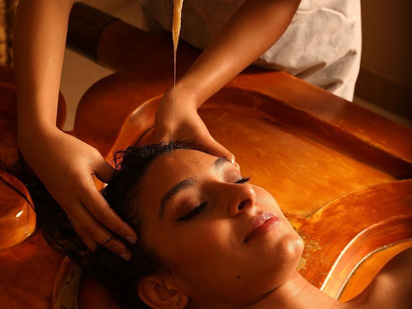 masseur performing shiro abhyangam on a guest