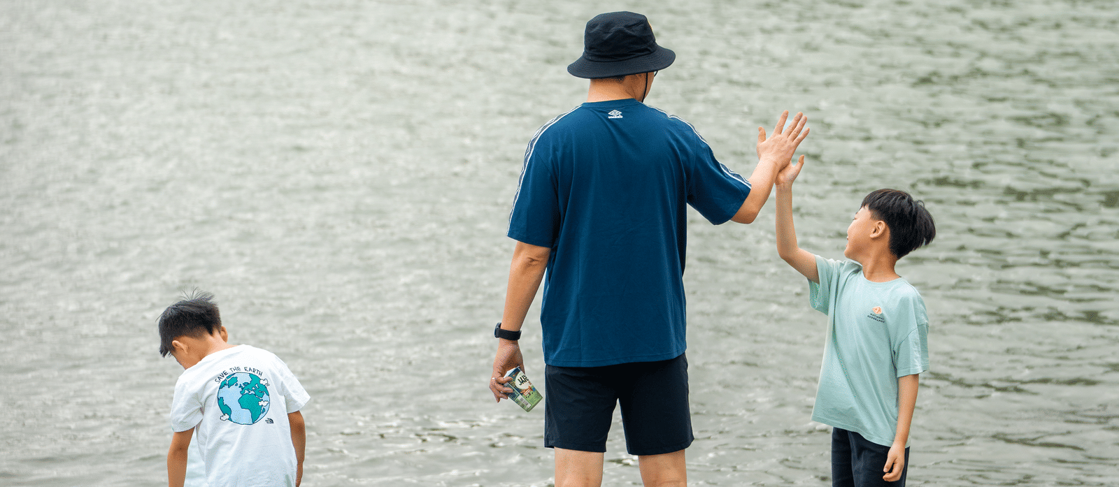 A man with two kids enjoying near the river side.