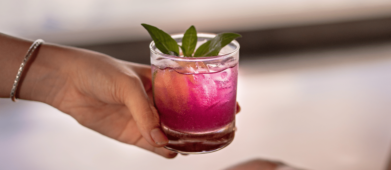 A person passing a glass f drink to another.