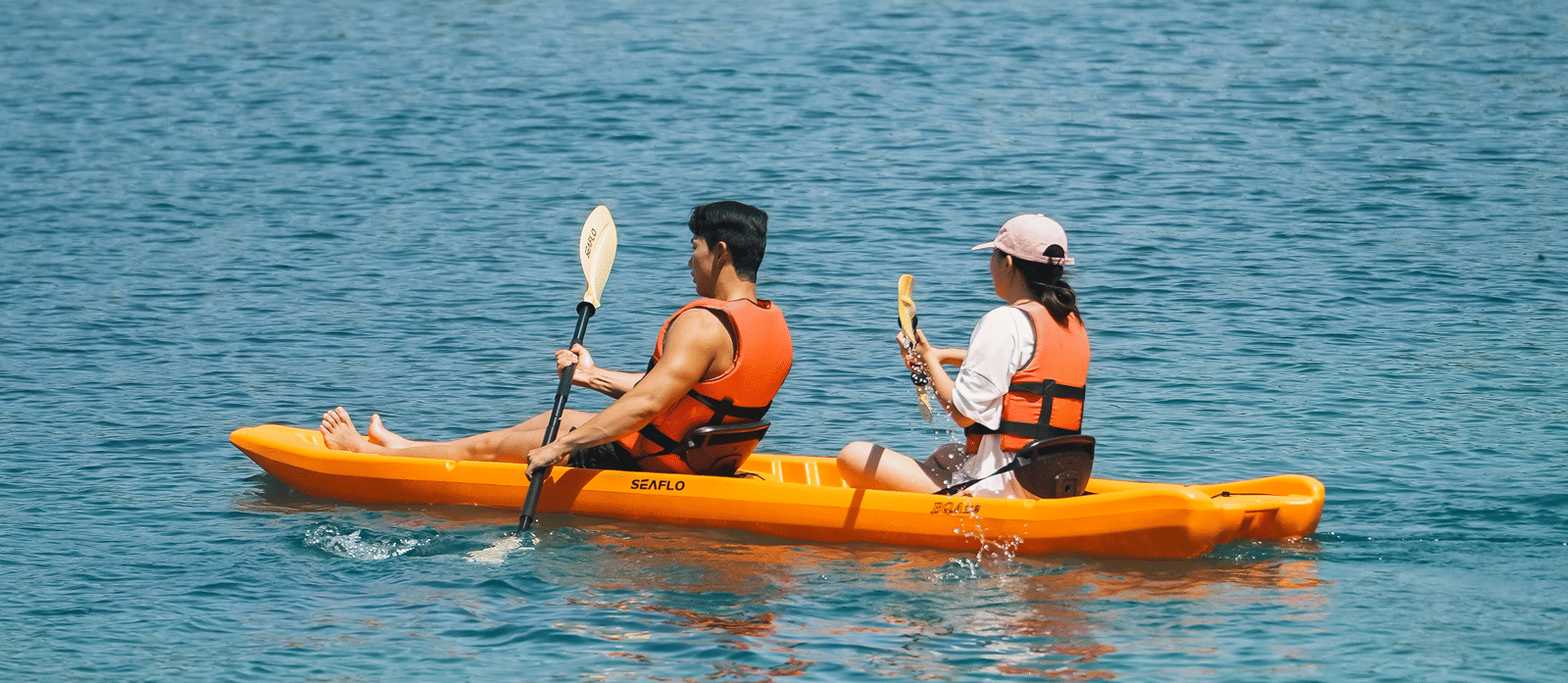 Two people kayaking on a boat near Alibu Resort Nha Trang in a sea.