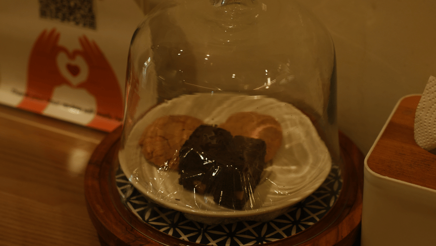A close-up view of a small dessert on a round plate sitting on a wooden counter surface at Oceanature Resort, Alibaug.