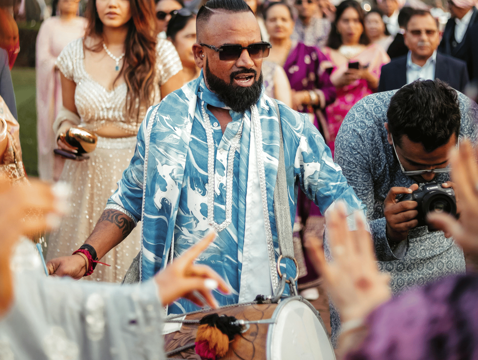 Guests celebrating at a lively outdoor Indian wedding event, capturing festive energy and colourful attire.