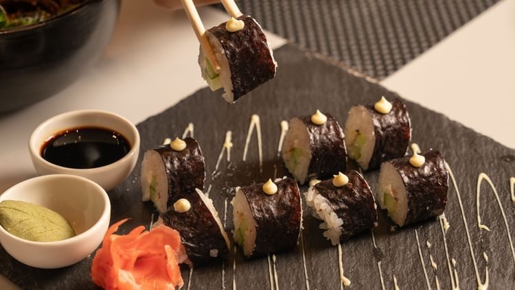 A plate of sushi with a hand picking it up at Ananta Spa and Resort, Ajabgarh