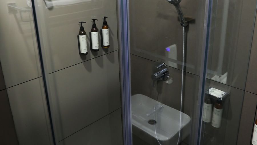 Glass-enclosed shower area with mounted toiletries at Hotel Kyzen HiTech City – Your Zenly Stay.