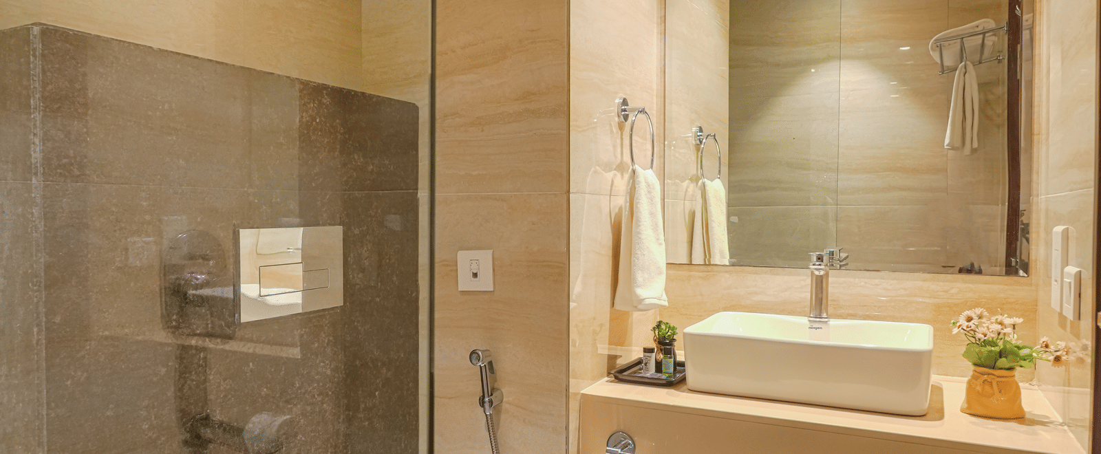 A clean, brightly lit hotel bathroom with a circular sink, large mirror, and a glass-enclosed shower area at BluSalzz Select City Centre, Amritsar.