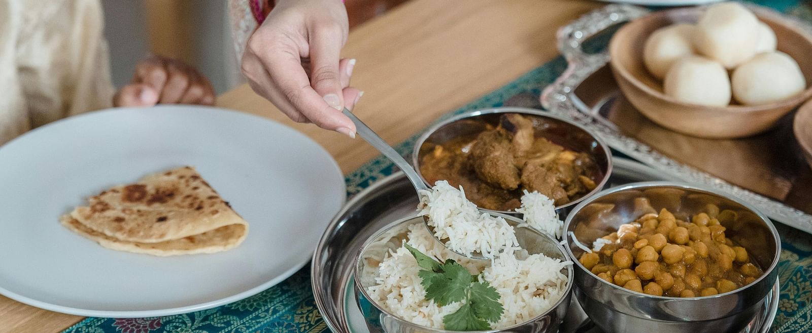 People sharing a meal with various dishes on a table, including flatbread and small bowls of food.