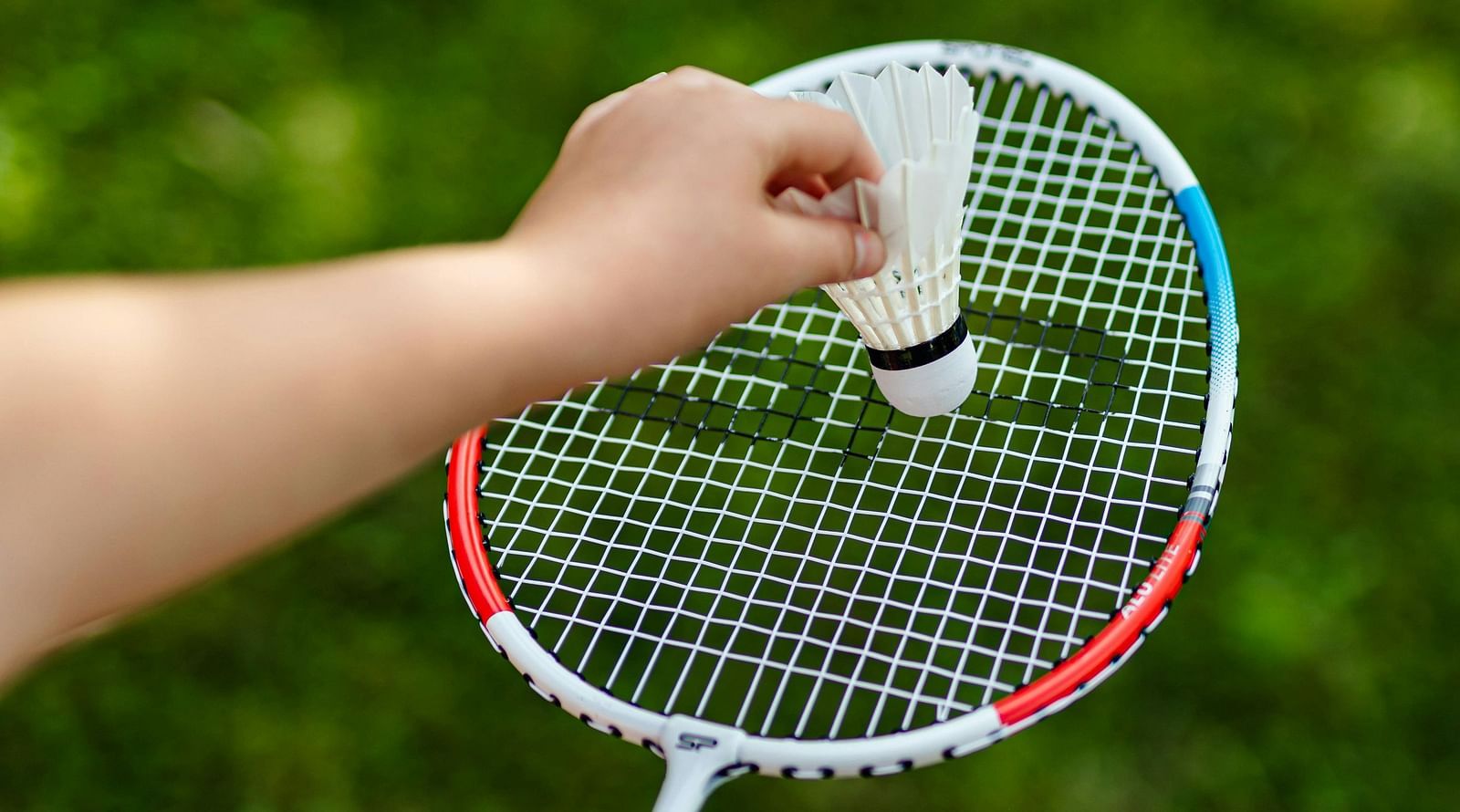 image of a badminton racket with a shuttle cock against a beautiful grass