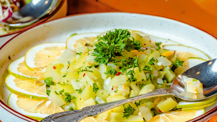 A creamy vegetable dish garnished with herbs at Marble Arch, found at Noor-Us-Sabah Palace, Bhopal, displayed alongside other appetisers on a wooden buffet.