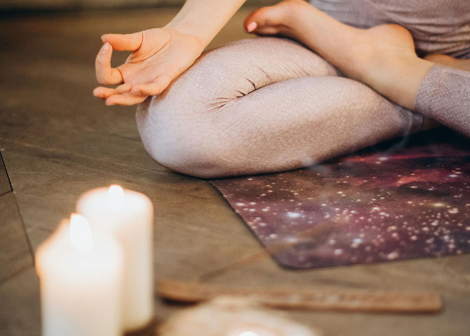 A woman on a prayer mat meditating while a candle is placed near her.