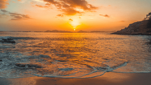 the sun setting behind the sea