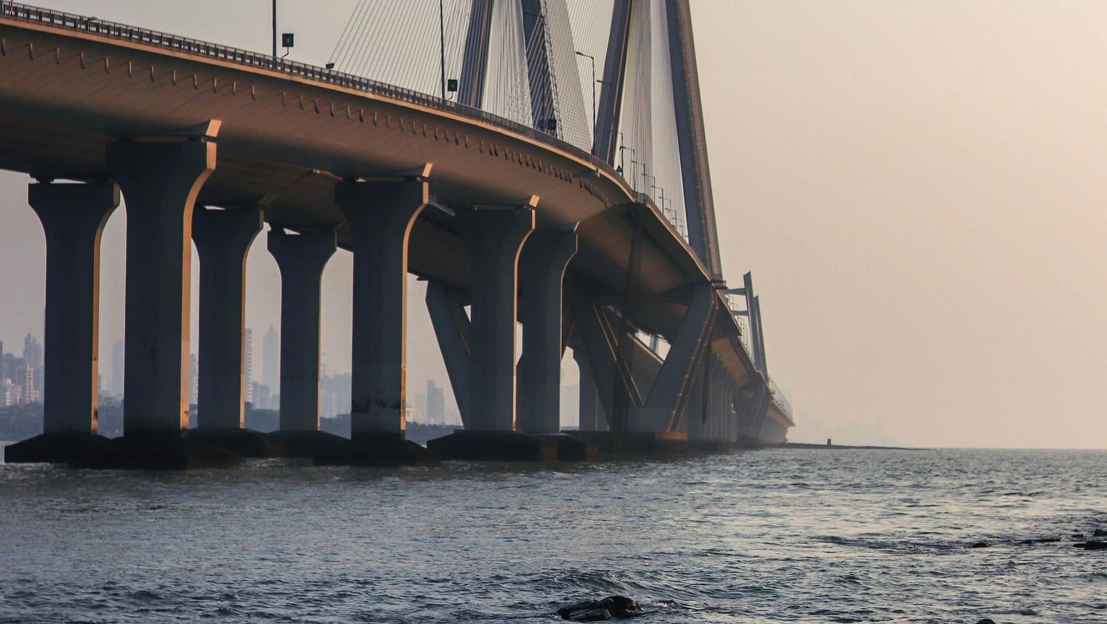 View of a cable-stayed bridge with its towers and suspension cables, surrounded by water and mist.