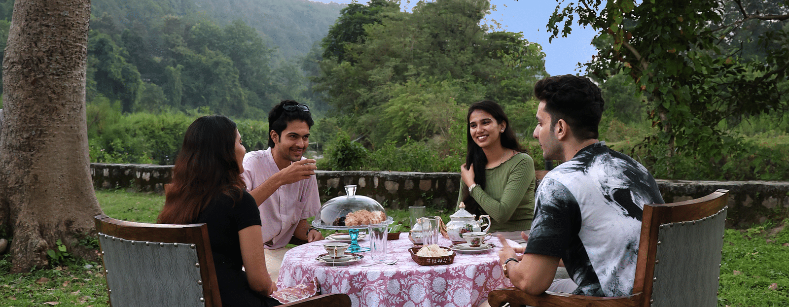 A lavish open-air dining setup with people enjoying a meal during the day at The Sylvan Retreat, Dehradun.