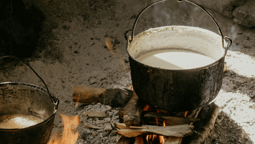 a pot with milk kept on a man made fire with ashes on the floor - Unique Sweets Laitumkhrah Shillong