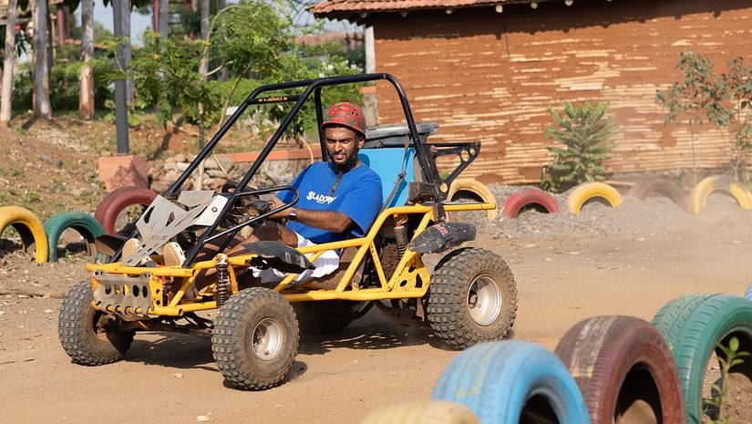 An individual driving a buggy car along a muddy road at VITS Roccia Hill Resort & Adventure Park