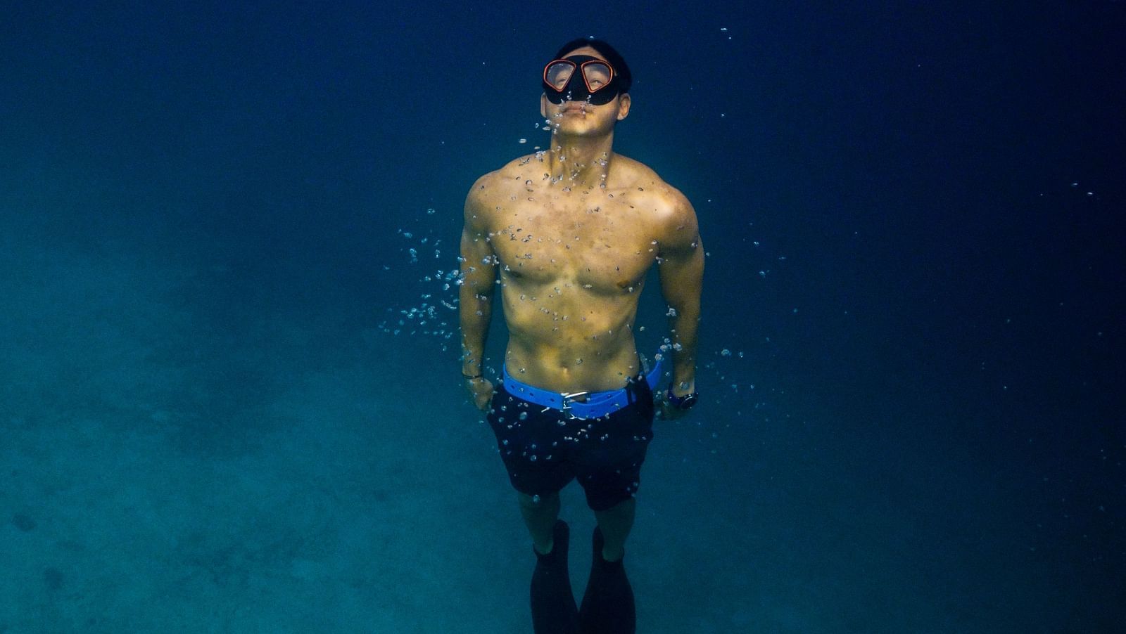 Person floating in deep blue sea, viewed from above, near Flower Island Resort.