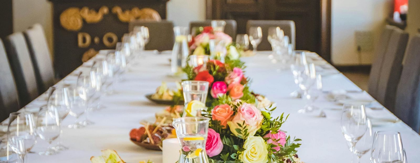 image of a closed banquet hall with crockery lined up with flowers put in the middle of the table