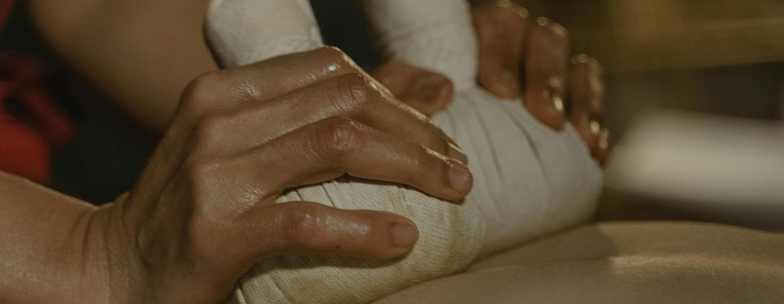 A masseuse using cloth bundles to press the back of a person.