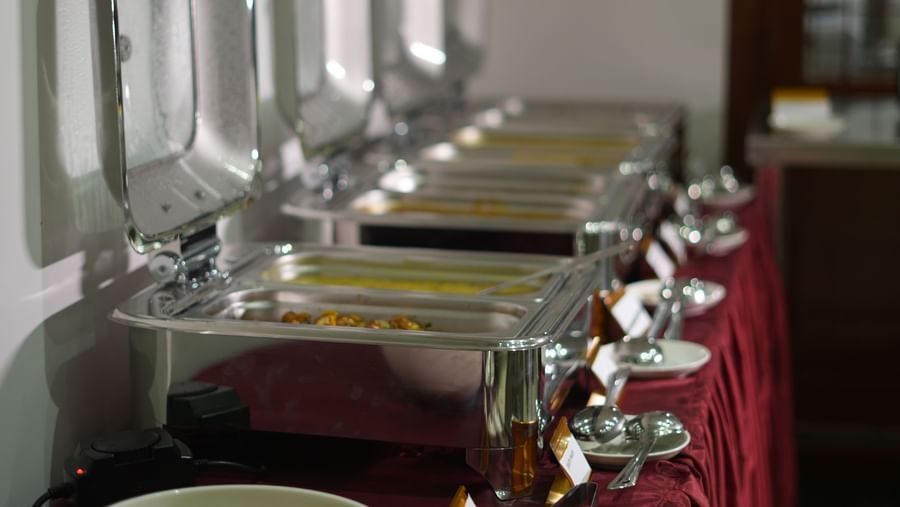 The buffet counter featuring several chafing dishes with their lids open at WOW Naturefull Resorts.