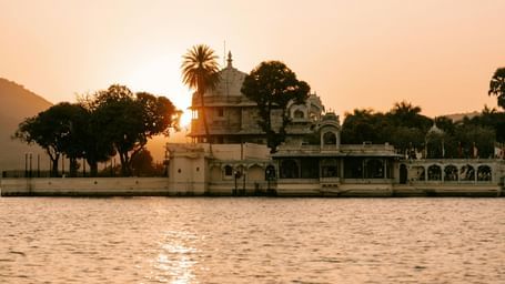 Jagdish Temple in Udaipur seen during a sunset, located near a water body.