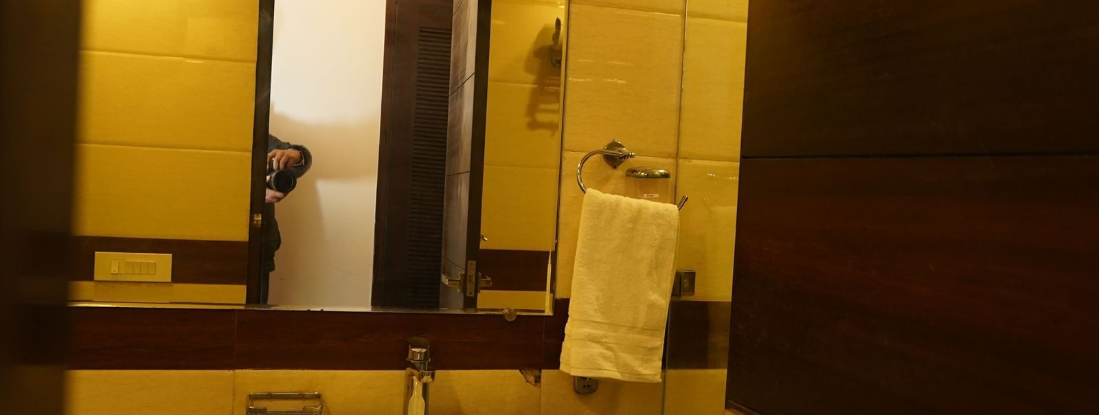 Bathroom at Hotel room in Hotel Dreamland, Chandigarh with vanity shelf below sink, hand towel and mirror.