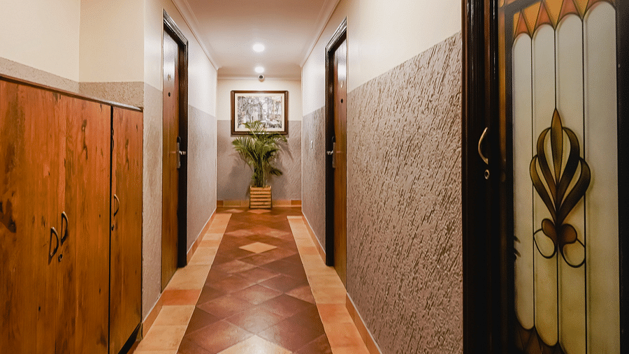 A narrow hallway with wooden doors and polished flooring - Cross Roads Inn, Bengaluru