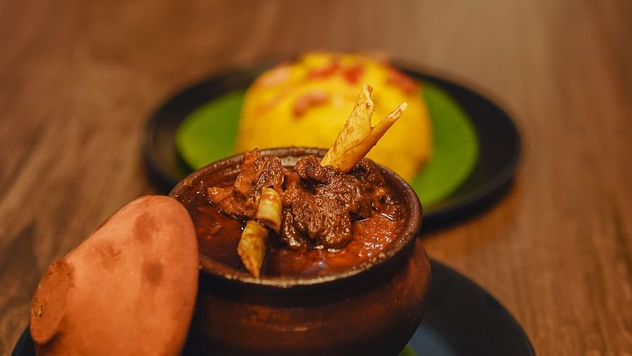 image featuring a mutton preparation served in an earthen pot with yellow rice - Dip Holidays, Birbhum