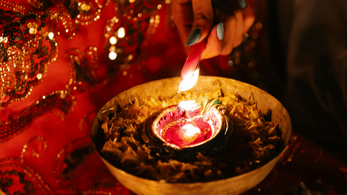 a woman lighting the lamp surrounded by flower petals