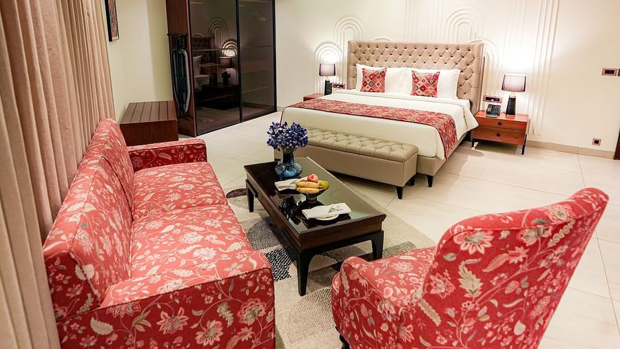 A portrait image of a suite with a upholstered chair, a upholstered sofa, a teapoy and a queen size bed - NAMAMI BY ZENQ BANKHANDI