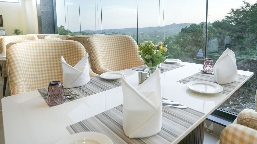 A close-up shot of a dining table situated near a large window, providing views of the mountains at our restaurant in Kangra - NAMAMI BY ZENQ BANKHANDI