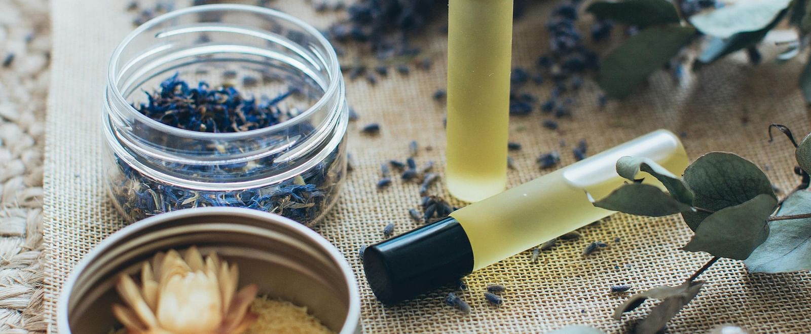 A collection of spa treatment ingredients, including dried lavender, essential oils, and a candle.
