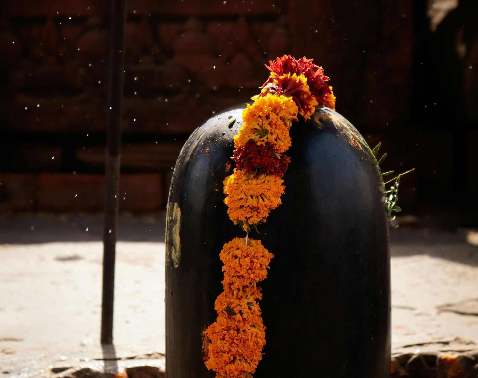 A close up shot of a Shivling adorned with a flower garland.