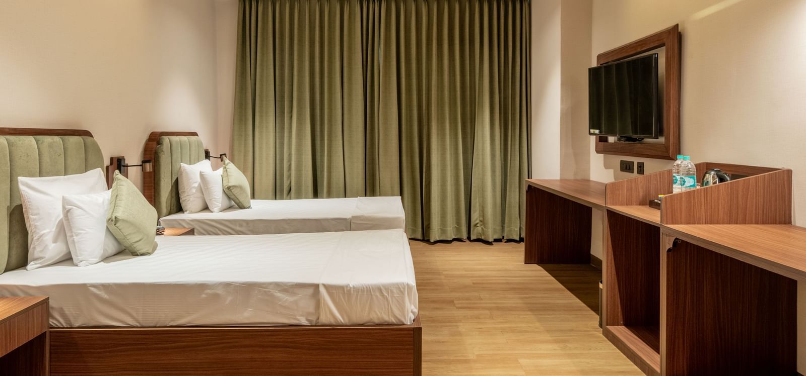 Spacious room with twin beds, wooden furniture, and a ceiling fan in a warm ambience at Hotel Highway King, Neemrana.