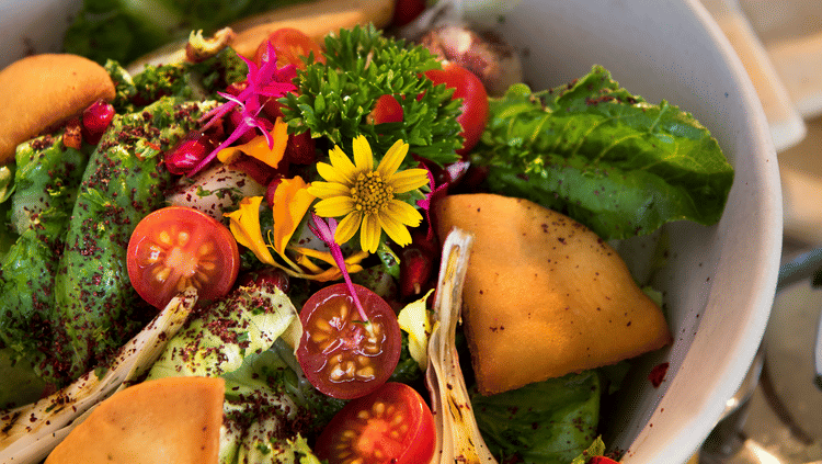 Colourful garden salad with lettuce, cherry tomatoes, cucumber, edible flowers & toasted bread—freshly served at Aramness.