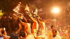 Devotees performing an evening aarti with flames rising against the night sky during a religious ritual.