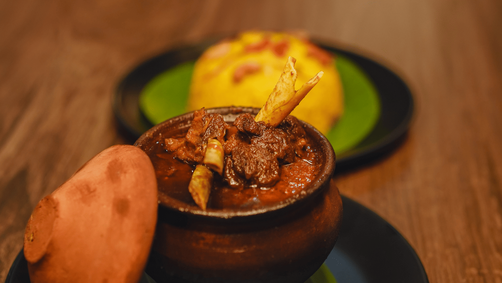 A mutton dish served in an earthen pot with yellow rice at Dip Holidays.