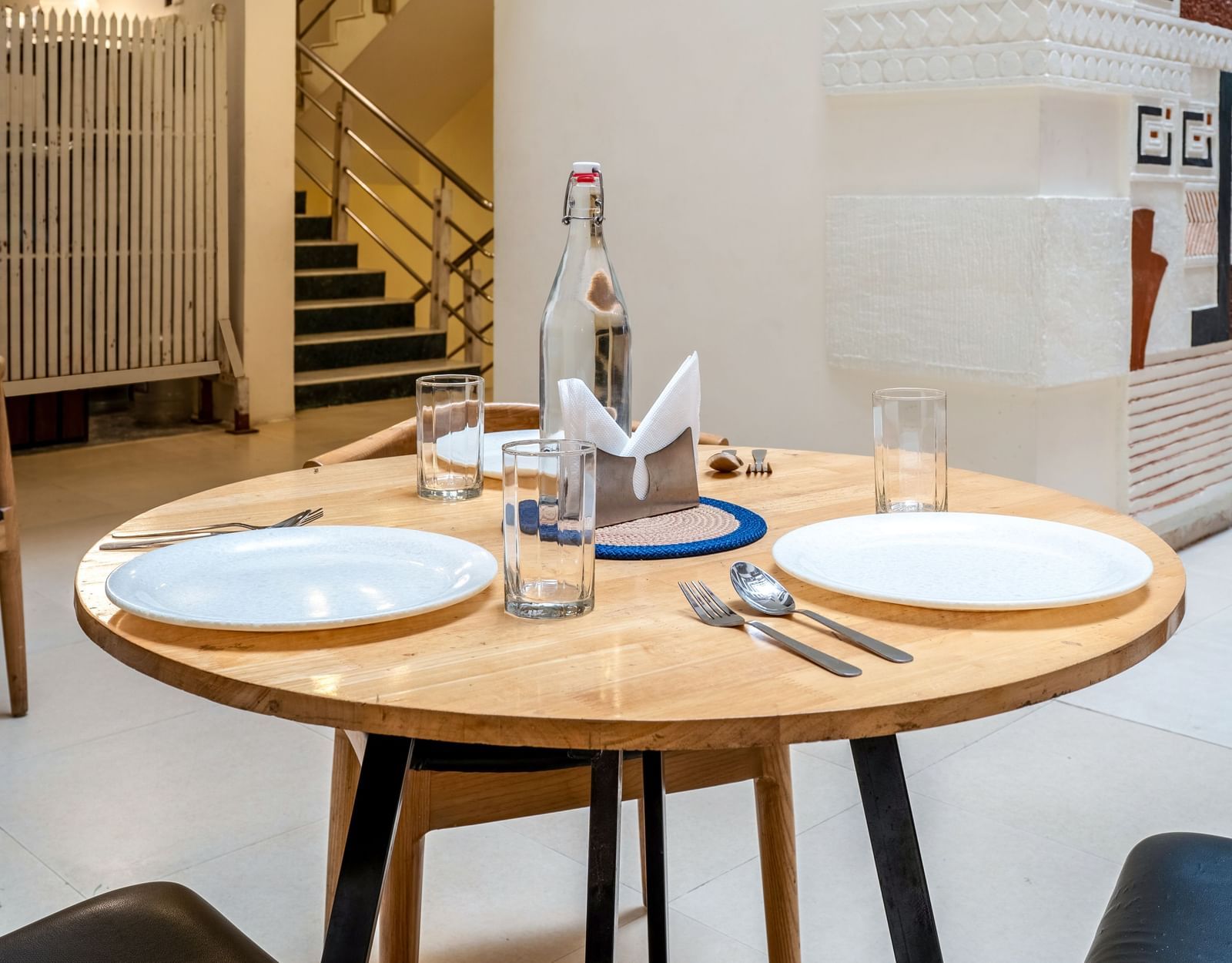 A round dining table set for 2 with plates, glasses, and cutlery - Monday Hotels HITEC City, Hyderabad