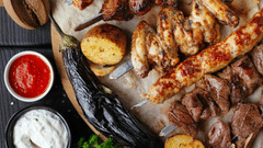 Platter of grilled kebabs served with dips and fresh vegetables.