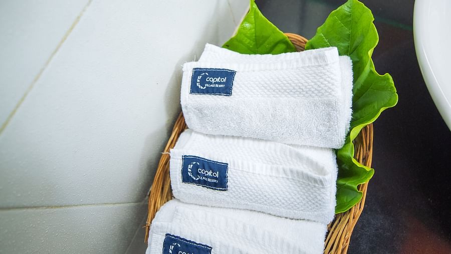 Towels in a basket near a sink at one of the rooms in Capitol Village Resort, Madikeri