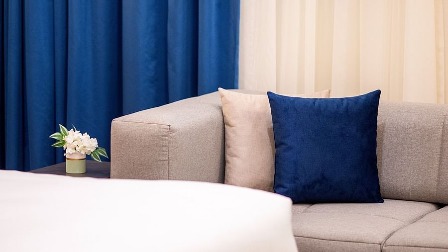 a Sofa in the background with curtains next to it inside one of the rooms - La Maison Hotel, Doha