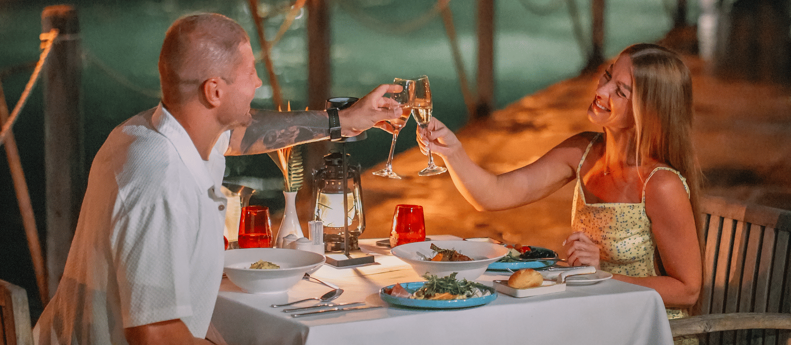 A couple in celebrating their Honey moon in Alibu Resort, Vietnam where two people are bringing their glasses together to celebrate near the beach.