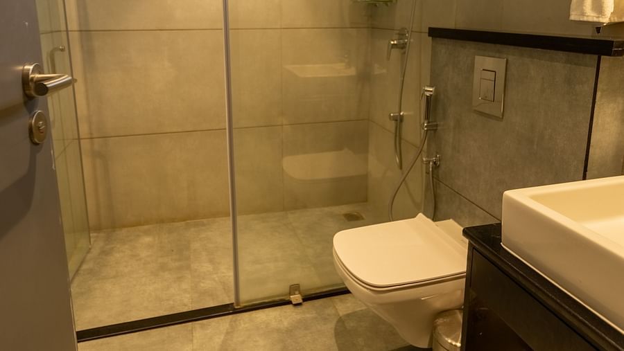 image of the bathroom featuring a shower cubical separated by a glass partition at the luxury group stay villa - Darza Resorts