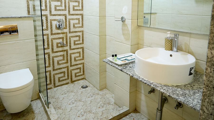 A compact bathroom with a shower cubicle, a sink, and a mirror, showing essential amenities - Asian Suites Cyber Park, Gurgaon