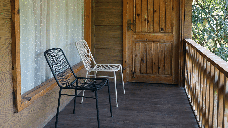 The balcony with chairs facing the view at the Pinewood Cottage at the Sylvan Retreat, Dehradun.