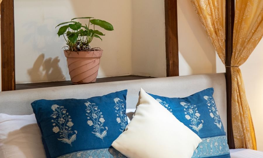 An image of a yellow canopy bed with blue pillows  at Lamrin Ucassaim Hotel, Goa